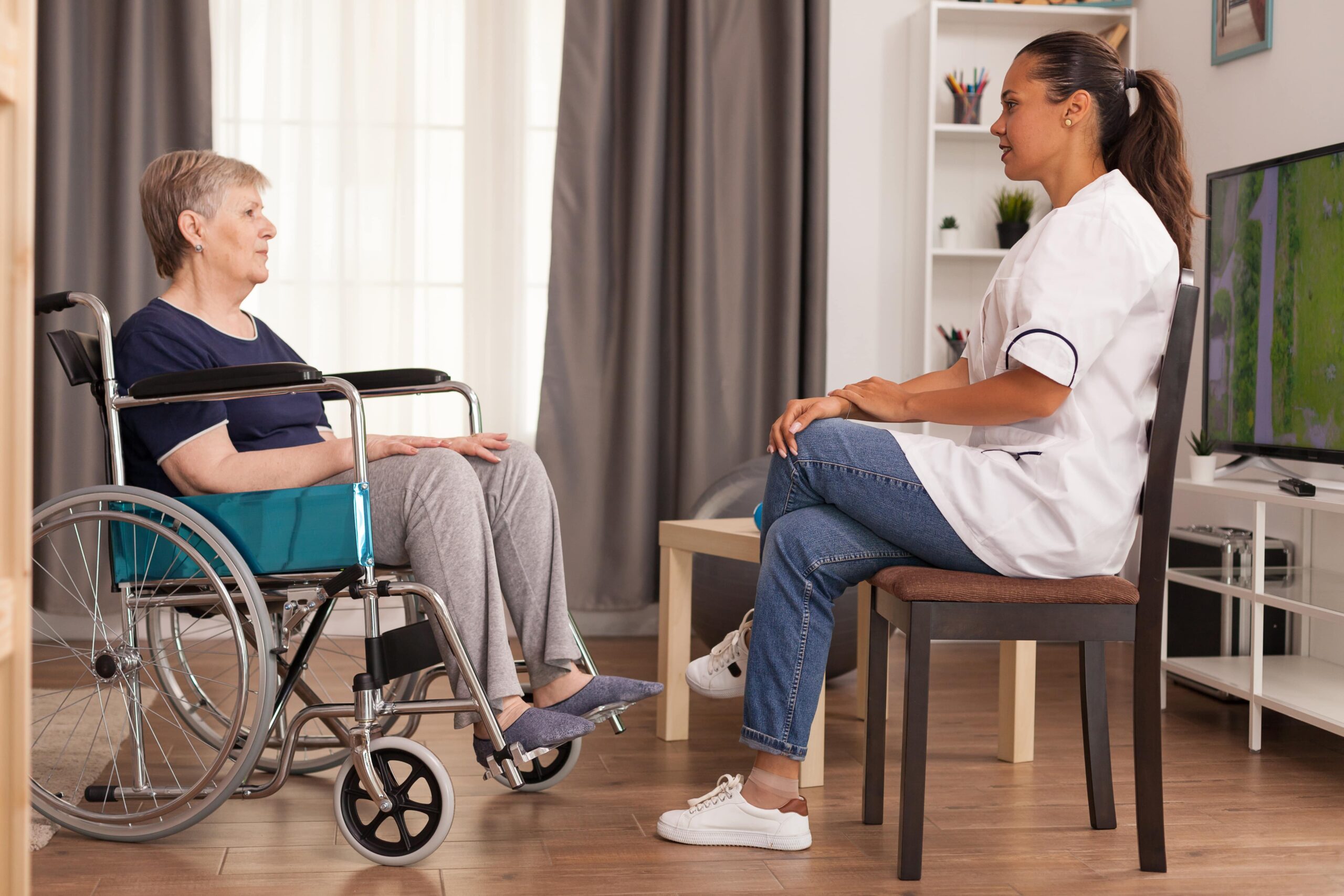 Caregiver talking with a disabled woman sitting on the wheelchair