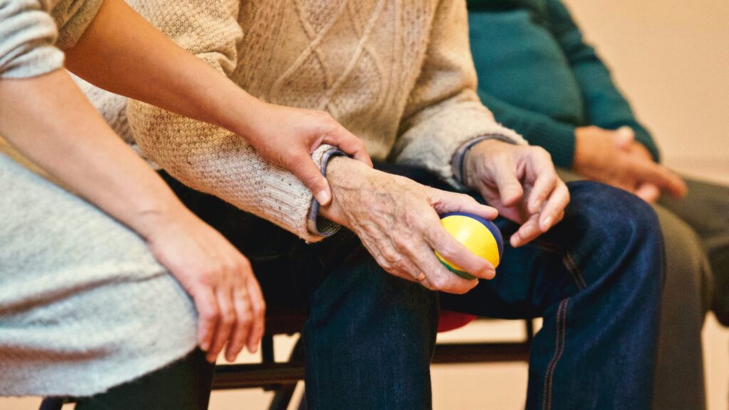 An elderly guy holding a stress ball undergoing palliative care