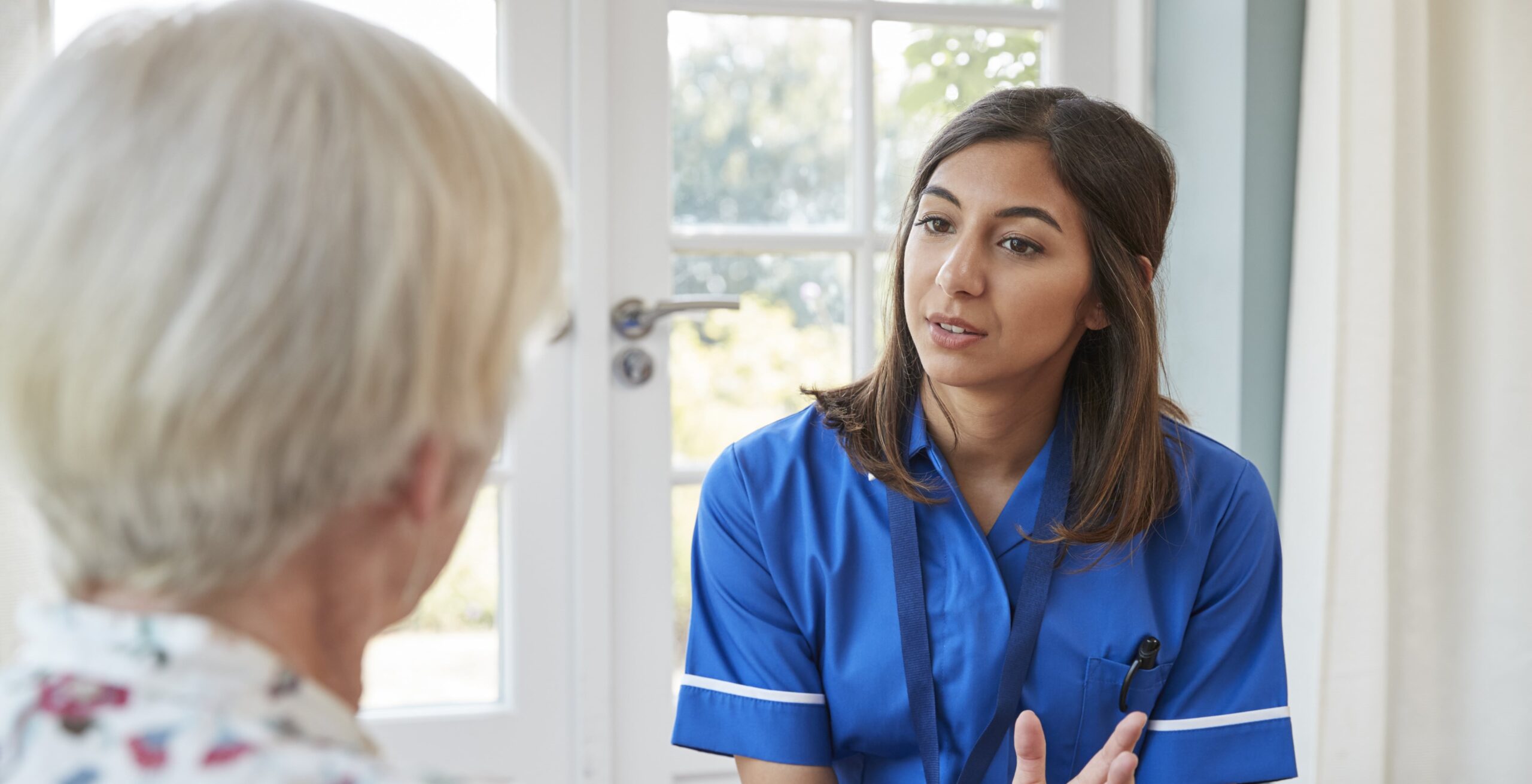 Female domiciliary care service worker speaking with a female Senior