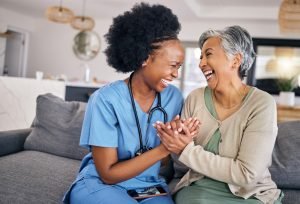 Senior woman cheerfully conversing with her female domiciliary care provider